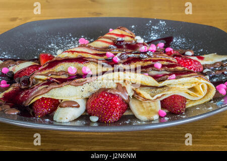 Libre de la crêpe avec crème au chocolat, chocolat, fraise et banane servi sur plaque gris sur une table en bois Banque D'Images
