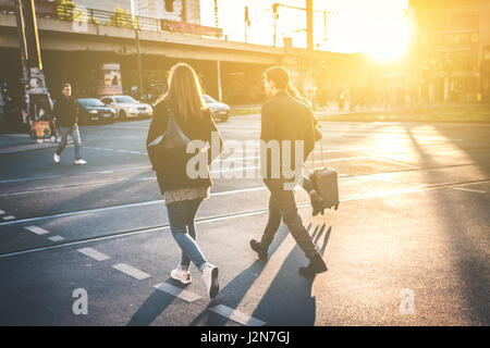 Couple walking on street - couple crossing street pendant le coucher du soleil Banque D'Images