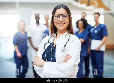 Femme médecin multiraciale, debout devant l'équipe médicale à l'hôpital. Looking at camera and smiling Banque D'Images