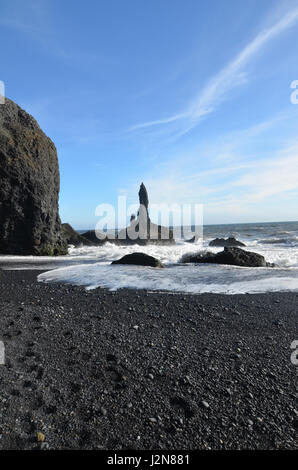 La mer d'Islande Reynisdrangar pile situé au large de la côte de la plage de sable noir. Banque D'Images