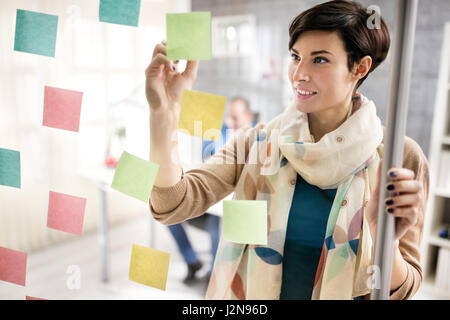 Designer femme faire régime sur les notes sur verre à design studio Banque D'Images
