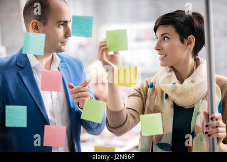 Autocollants colorés sur la façade de verre aident les femmes designer et son associé dans le travail Banque D'Images