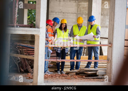 Équipe de jeunes spécialistes qui étudient l'architecture blue print à air libre construction site Banque D'Images