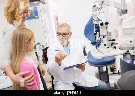 Médecin homme parler à son patient avec mère dans eye clinic Banque D'Images