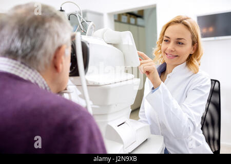 Jeune femme médecin travailler avec un appareil utilisant les yeux du patient Banque D'Images