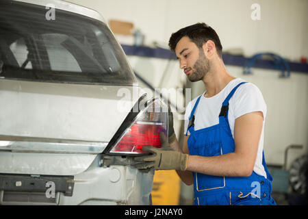 Mécanicien arrange voiture rétro-éclairage Banque D'Images