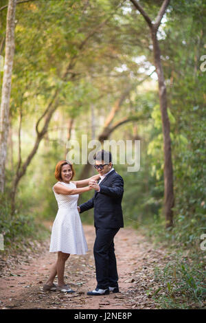 Un couple en tenue habillée costume noir et blanc romantique robe danser dans la forêt de pins avant mariage, Thaïlande Banque D'Images