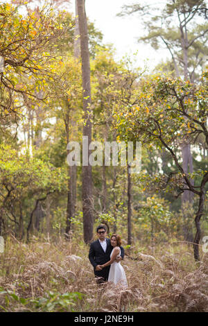 Un couple en tenue habillée robe blanche et costume noir romance dans la forêt de pins avant mariage, Thaïlande Banque D'Images