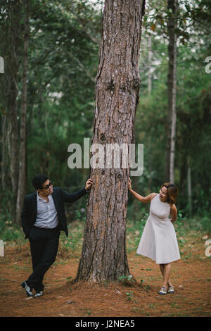 Un couple en tenue habillée robe blanche et costume noir romance dans la forêt de pins avant mariage, Thaïlande Banque D'Images