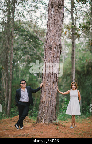 Un couple en tenue habillée robe blanche et costume noir romance dans la forêt de pins avant mariage, Thaïlande Banque D'Images