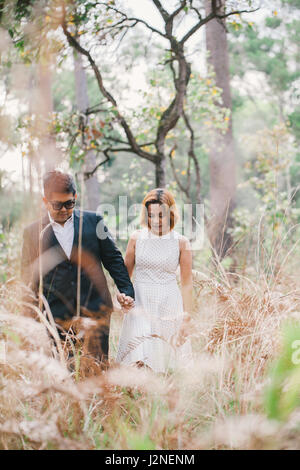 Un couple en tenue habillée robe blanche et costume noir romance dans la forêt de pins avant mariage, Thaïlande Banque D'Images