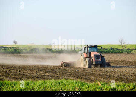 Un tracteur avec une charrue fixe le sol. La culture du sol sur le terrain pour le semis. Banque D'Images