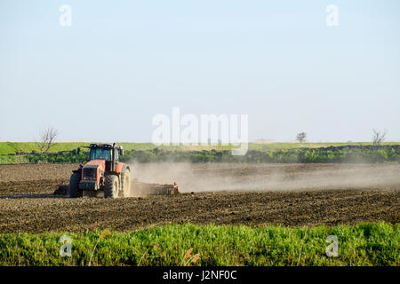 Un tracteur avec une charrue fixe le sol. La culture du sol sur le terrain pour le semis. Banque D'Images