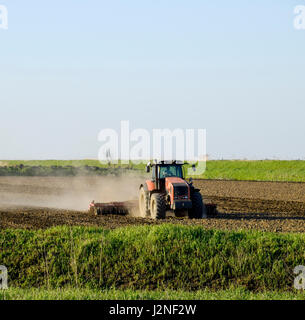 Un tracteur avec une charrue fixe le sol. La culture du sol sur le terrain pour le semis. Banque D'Images