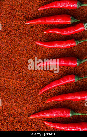 Red Hot Chili Peppers, épices populaires concept - motif décoratif en forme de marches de l'escalier de chili red hot pepper pods sur un fond brun de paprika, de mise à plat, à la verticale. Banque D'Images