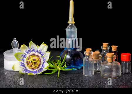 Spa magnifique composition de fleurs bleu passiflora, cosmétiques et parfums mortier sel bouteilles vides sur le zen stones avec la rosée, Close up Banque D'Images