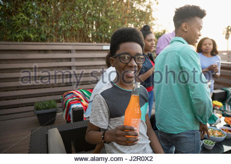 Portrait of smiling African American boy drinking soda à l'orange sur le pont d'été avec la famille