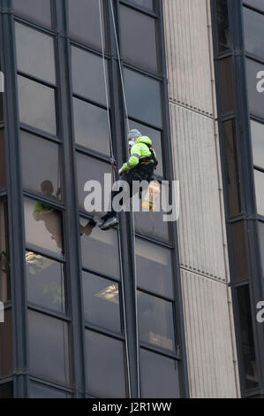 Un homme balance un bloc de bureau de grande hauteur à Cardiff au Pays de Galles. Les herbicides pulvérisation Banque D'Images