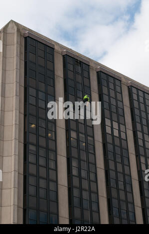 Un homme balance un bloc de bureau de grande hauteur à Cardiff au Pays de Galles. Les herbicides pulvérisation Banque D'Images