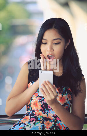 Femme Asiatique à la surprise de son téléphone portable Banque D'Images