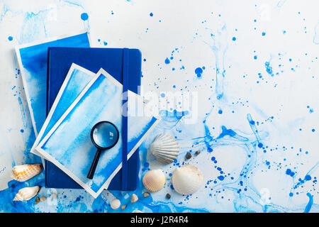 Billet d flatlay marine avec les coquillages, sketchbook, loupe et boussole dessin sur un fond d'aquarelle Banque D'Images