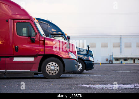 Deux camions semi de différentes couleurs se tenir dans une rangée à l'aire de stationnement en prévision de l'ouverture de chargement - déchargement. Profil de couleur Banque D'Images