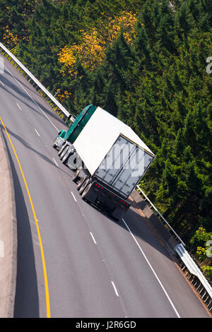 La grande remorque semi-remorque classique robuste qui transporte des marchandises dans la remorque de chargement à sec intérieure se déplace sur une large autoroute multi-bande avec des lignes de séparation Banque D'Images
