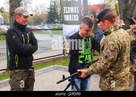 Un soldat britannique de Battle Group Pologne démontre le poids de sa mitrailleuse à un étudiant polonais au Stol DOSKONALENIA ZAWODOWEGO, une école militaire, à Gizycko, Pologne 25 avril. Le groupe tactique a participé à une exposition statique pour les élèves du secondaire de l'école au cours de la journée portes ouvertes permettant aux élèves et les citoyens polonais d'interagir avec l'unité multinationale et explorer son équipement de combat. L'unique formation d'américains, britanniques et soldats roumains sont en service avec Polish 15e Brigade mécanisée de soldats comme une force de dissuasion dans le nord-est de la Pologne à l'appui de l'OTAN Banque D'Images