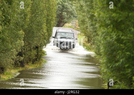 16 juillet 2012 - Les véhicules roulant dans l'inondation sur les niveaux de Somerset sur la route entre Glastonbury et Godney Banque D'Images