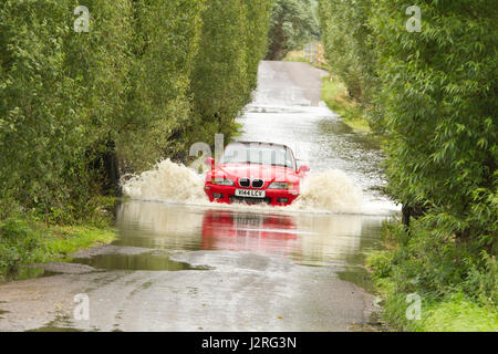 16 juillet 2012 - Les véhicules roulant dans l'inondation sur les niveaux de Somerset sur la route entre Glastonbury et Godney Banque D'Images