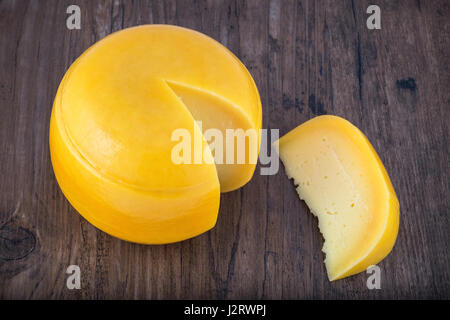 Tête de fromage avec une tranche coupée sur table en bois. Selective focus Banque D'Images