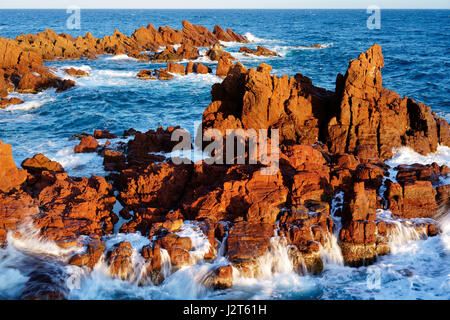 Dernière lumière de la journée sur une mer agitée s'écrasant sur des rochers rouges. Estérel massif, Saint-Raphaël, Var, Provence-Alpes-Côte d'Azur, France. Banque D'Images