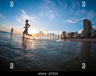 RIO DE JANEIRO - le 2 février 2013 : Silhouettes passent devant le coucher du soleil sur la rive de la plage d'Ipanema. Banque D'Images