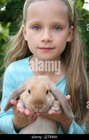 Une petite fille possède un jeune lapin nain Banque D'Images