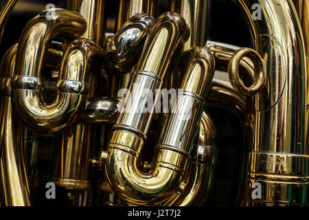 Détail de l'tuyaux en laiton d'un tuba. Résumé fond montrant les courbes et les articulations de cette bande en laiton poli instrument de musique. Banque D'Images