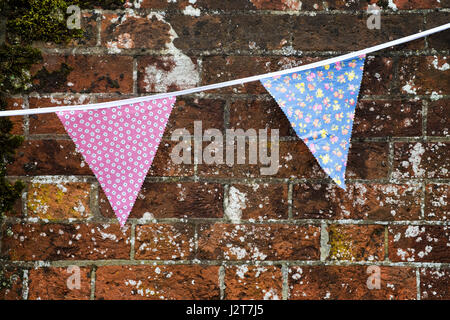 Imprimé floral festif bunting pendaison contre l'ancien mur de briques Banque D'Images