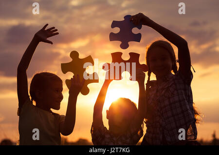 Silhouette de trois enfants heureux qui jouent sur le terrain à l'heure du coucher du soleil. Ils s'amusant sur la nature. Le concept d'enfants sont prêts à aller t Banque D'Images