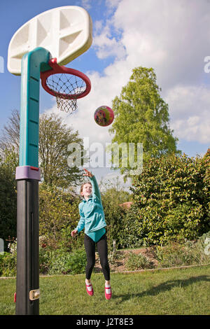 Vue verticale d'une jeune fille jouant au basket-ball dans le jardin. Banque D'Images