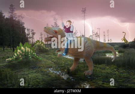 Un petit garçon fantaisie équestre sur un dinosaure Banque D'Images
