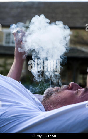 Un homme d'âge moyen bénéficie d'un cigare dans le jardin Banque D'Images