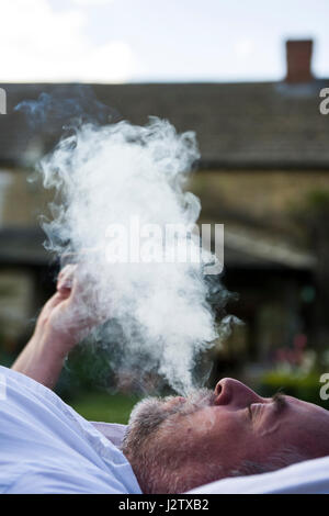 Un homme d'âge moyen bénéficie d'un cigare dans le jardin Banque D'Images