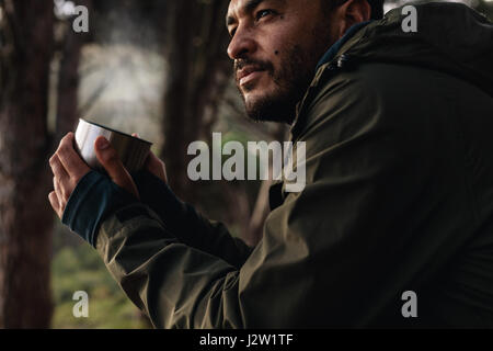 Gros plan de l'atmosphère jeune homme le café en plein air. Male hiker prendre repos et de boire du café frais. Banque D'Images