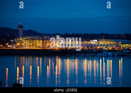 Compte tenu de la soirée l'aéroport de Portland avec tour de contrôle, l'éclairage et de réflexion dans la rivière, où les bateaux sont stationnés. Dans les lumières des voitures parking Banque D'Images