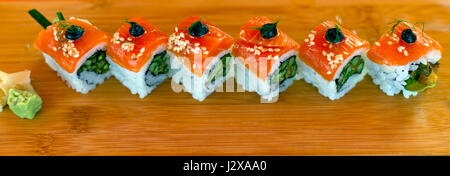 Couper en carrés égaux Rôle de l'avocat farci de sushi, avec des couches de poissons saumon, olives, wasabi, enveloppés dans du riz blanc. Plié en diagonale Banque D'Images