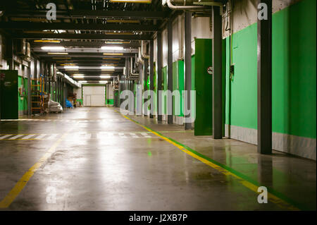 Corridor dans un bâtiment de production avec des murs verts et un plancher de béton en vrac Banque D'Images