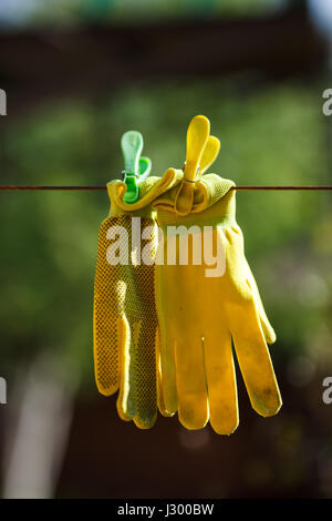 Photo gros plan de gants jardin jaune accroché à une corde. Banque D'Images