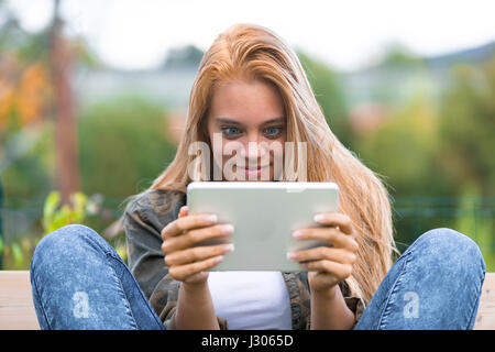 Choqué young woman making funny faces à une tablette numérique, voyant quelque chose de surprenant sur l'internet Banque D'Images