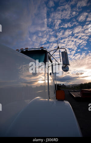 Un fragment d'un grand camion blanc semi avec le pare-brise et des miroirs sur l'arrière-plan d'un nuage ciel spectaculaire ondulé reflète sur un plan brillant Banque D'Images