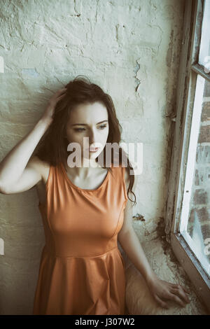 Jeune femme sérieuse à la recherche par la fenêtre Banque D'Images