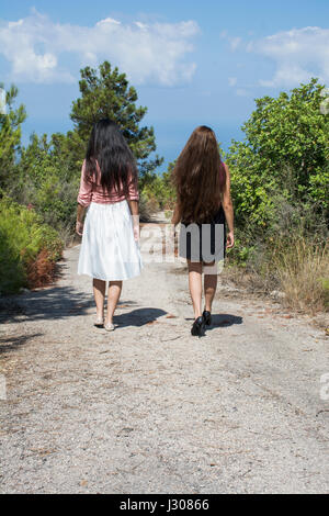 Vue arrière de deux jeunes femmes marche loin ensemble sur une route de campagne Banque D'Images